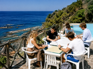 Gruppe von Studenten sitzen an einem Tisch und studieren das Meer überragend